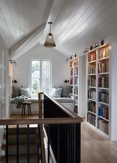 a living room with bookshelves and stairs leading up to the second floor area