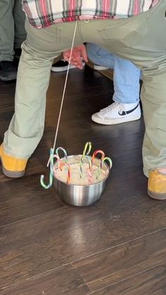 a man is bending over to put candy canes in a bowl on the floor