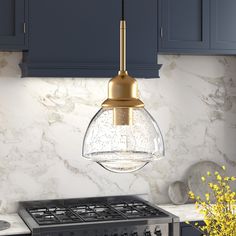 a kitchen with marble counter tops and blue cabinets, including a gold pendant light over the stove