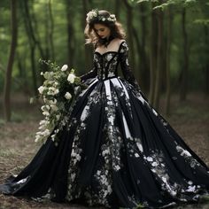 a woman in a black and white dress standing in the woods with flowers on her head