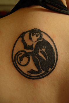 a monkey tattoo on the back of a woman's upper arm, with a circular design