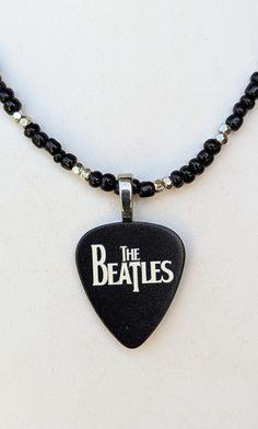 the beatles guitar pick pendant on a beaded necklace with black beads and silver clasp