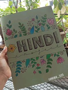 a person holding up a book with the word hindu written in floral designs on it