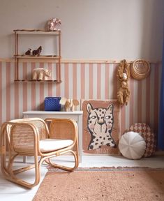 a room with pink and white striped wallpaper, wicker chairs and shelves on the walls