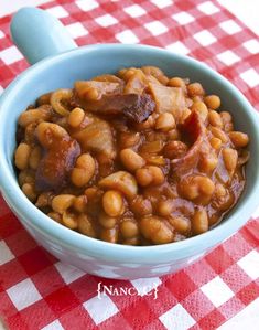 a blue bowl filled with beans on top of a red and white checkered table cloth