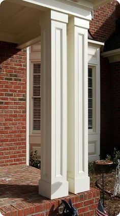 an american flag sitting on the front steps of a brick house with white columns and pillars