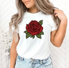 a woman wearing a white shirt with a red rose on it