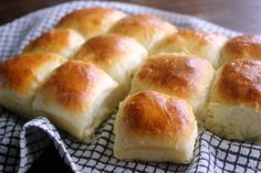 a bunch of bread rolls sitting on top of a cloth covered table next to a black and white checkered napkin