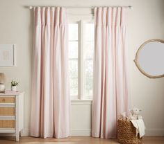 a pink curtain hanging in front of a window next to a white dresser and mirror