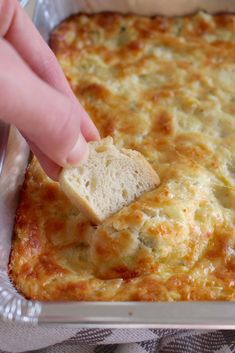 a person dipping bread into a casserole dish