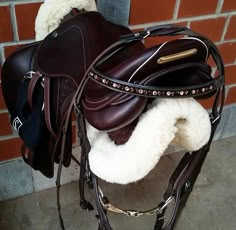 a brown and white horse saddle sitting in front of a brick wall