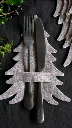 a fork and knife sitting on top of a table next to christmas tree shaped napkins