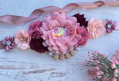 a bunch of flowers that are sitting on a wooden table next to some pink ribbons