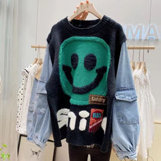 a sweater with an alien face on it is hanging in front of a rack of clothes