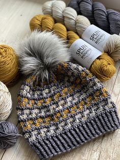 several skeins of yarn sitting next to each other on a wooden floor with balls of yarn in the background