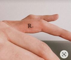 a person's hand with the letter r tattooed on it