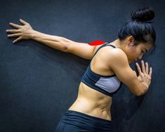 a woman leaning against a wall with her arms stretched out and hands behind her back