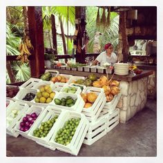 a man standing behind a counter filled with lots of fruit