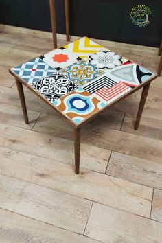 two wooden chairs sitting on top of a hard wood floor next to a tiled table