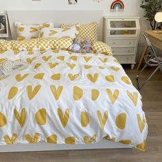 a bed with yellow hearts on it in a bedroom next to a desk and chair