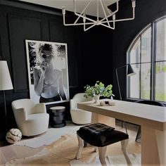 a room with black walls, white chairs and a wooden table in front of a large window