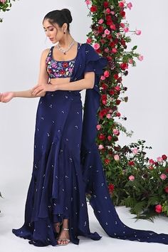 Midnight blue attached cancan ruffed lehenga saree with all over crystal drops embellishments and an attached drape. Paired with a backless halter neck padded blouse with multi colored sequins bloom embroidery. - Aza Fashions Ruffled Dresses For Navratri, Fitted Ruffled Saree, Fitted Draped Sharara With Pallu, Fitted Anarkali Dress With Draped Style, Fitted Anarkali Draped Dress, Fitted Draped Anarkali Dress, Designer Ruffled Dresses For Eid, Sleeveless Ruffled Sharara For Festive Occasions, Fitted Draped Dress With Resham Embroidery