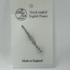 a small silver plated flute charm in a package on a white background with the caption made in england