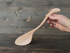 a hand holding a wooden spoon on top of a table