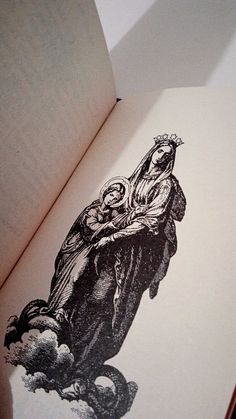 an open book with black and white drawings on it's cover, depicting the virgin mary