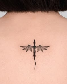 the back of a woman's neck with a dragon tattoo on it