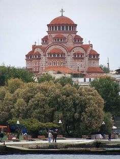 people are standing on the edge of a body of water in front of an old building