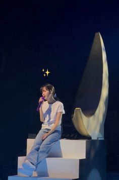 a woman sitting on top of a set of stairs with a microphone in her hand