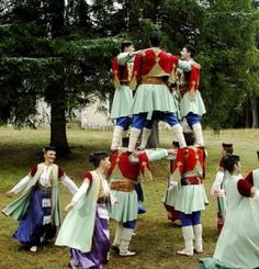 a group of people standing around each other on top of one another in the grass