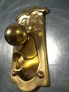 a golden door handle with a person holding a ball on it's back end