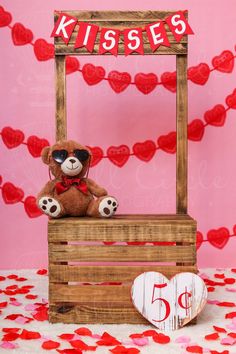 a brown teddy bear sitting on top of a wooden crate next to a red heart