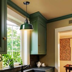 a kitchen with green cabinets and black counter tops in front of an open door that leads to a dining room