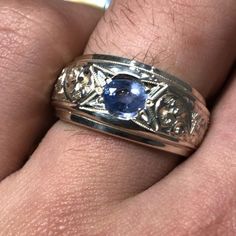 a man's wedding ring with a blue stone in it