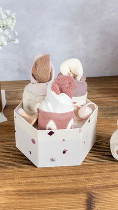 a white box filled with baby items on top of a wooden table next to a vase