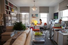 a living room filled with furniture next to a window covered in blinds and bookshelves