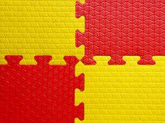 two pieces of red and yellow puzzle sitting next to each other on top of a floor