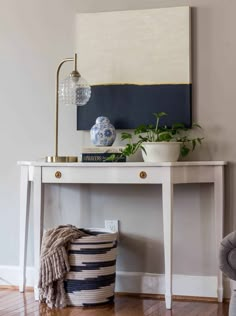 a white table with a blue and white painting on it next to a gray chair