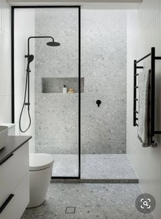 a bathroom with a walk in shower next to a white toilet and black accents on the walls