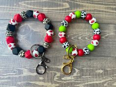 two bracelets with scissors and beads on a wooden surface, one is green, the other is red