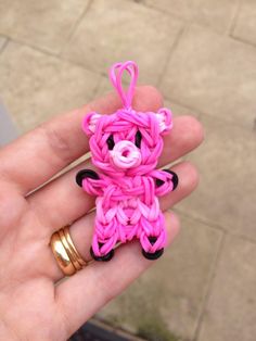 a hand holding a small pink and black bear ornament in it's palm