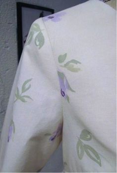 the back of a woman's dress with purple flowers and green leaves on it