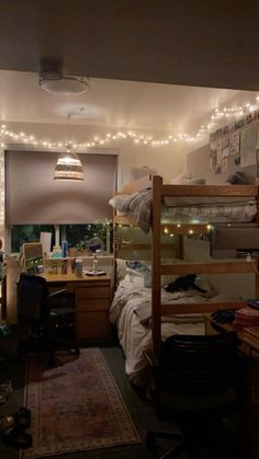 a dorm room with bunk beds and lights on the ceiling above it is lit up by string lights