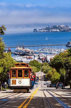 a cable car traveling down a street next to the ocean