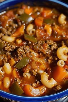 a blue bowl filled with pasta and meat soup