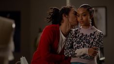 two young women are kissing each other in the living room, one is wearing a leopard print sweater