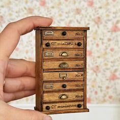 a hand holding a miniature wooden drawer